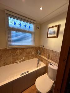 ein Bad mit einer Badewanne, einem WC und einem Fenster in der Unterkunft Toosey Lass - St Osyth creek in Saint Osyth