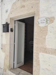 an open door in a stone building with a sign at Nel Vico Antico in Ostuni