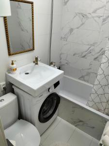 a bathroom with a sink and a washing machine at VIP Апартаменти in Dnipro