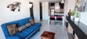 ein Wohnzimmer mit einem blauen Sofa und einer Küche in der Unterkunft Happy Nogalera Centro - Vistas al Mar in Torremolinos