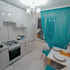a kitchen with white cabinets and a blue curtain at VIP Апартаменти in Dnipro +17 photos