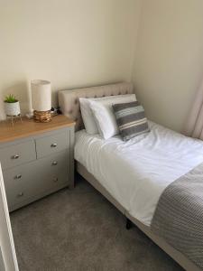 een slaapkamer met een bed en een nachtkastje met een wit bed bij The Cosy House in Hugglescote