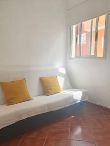 a white couch with two yellow pillows sitting under a window at CASA CORALES in La Mareta