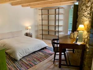 a bedroom with a bed and a desk and a table with a lamp at Habitaciones rurales en Colomers in Colomés