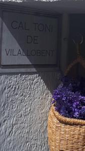 einen Korb mit lila Blumen vor einem Schild in der Unterkunft Cal Toni de Vilallobent in Vilallovent