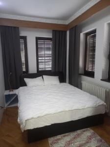 Schlafzimmer mit einem Bett mit weißer Bettwäsche und Fenstern in der Unterkunft Lion Guest House in Skopje