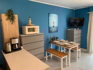 uma cozinha com uma mesa com um micro-ondas e uma televisão em Ferienwohnung "Roter Sand" em Burhave