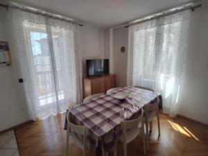 Residenza Arnica في مولفينو: غرفة طعام مع طاولة وكراسي وتلفزيون