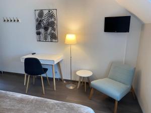 CourtilsにあるLe Relais de la Hardiesseのデスク、椅子、テーブルが備わる客室です。