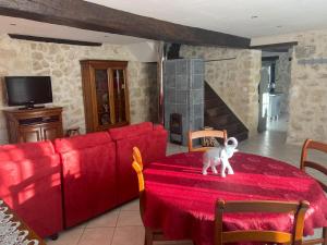 a red couch and a table with a stuffed animal on it at Gîte 8 personnes in Sainte-Croix-du-Mont
