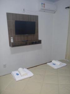 Pousada Cantinho في غرامادو: غرفة بها منشفتين بيض وتلفزيون بشاشة مسطحة