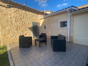 a patio with two chairs and a table and a building at Gîte 8 personnes in Sainte-Croix-du-Mont
