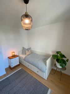 a white bed in a room with a potted plant at Gemütliche Wohnung am Federsee in Bad Buchau