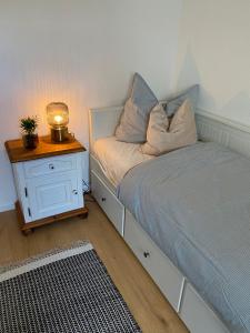 een slaapkamer met een bed en een nachtkastje met een lamp bij Gemütliche Wohnung am Federsee in Bad Buchau