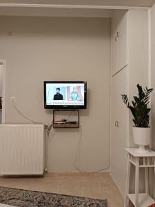 Κεντρικό ευρύχωρο στούντιο με parking في لاريسا: تلفزيون بشاشة مسطحة على جدار أبيض في غرفة المعيشة