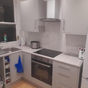 a kitchen with white cabinets and a stove top oven at Double Room with shared bathroom in private self-contained flat you will share with one other person in family house 2 minutes walk from Tufnell Park tube station 15 minutes walk from Camden Town in London