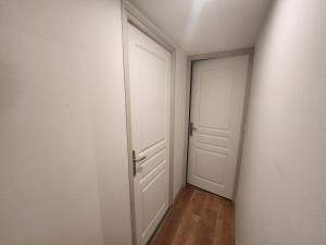un couloir vide avec une porte blanche et du parquet. dans l'établissement Spacieux 2 chambres, lumineux, à Bar-le-Duc