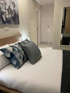 uma cama com almofadas num quarto em Apartamento Fibes-Congresos Parking Gratis em Sevilha