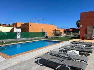 a swimming pool with lounge chairs next to a building at Villa Magna in Caleta De Fuste