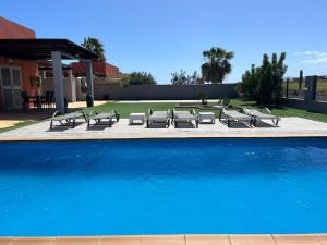 eine Gruppe von Liegestühlen und einem Pool in der Unterkunft Villa Magna in Caleta de Fuste