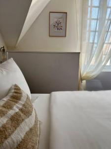 a bedroom with a white bed and a window at Le Gite de la Poterne, maison en bordure du Serein in Chablis