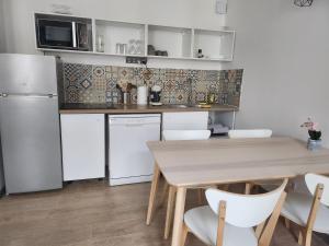 een keuken met een houten tafel en witte apparaten bij Spacieux 2 chambres, paisible in Bar-le-Duc