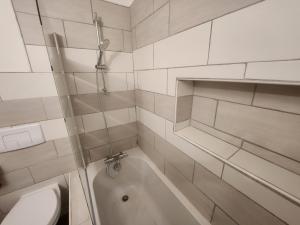 biała łazienka z wanną i toaletą w obiekcie Spacieux 2 chambres, paisible w mieście Bar-le-Duc