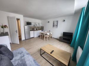 een woonkamer met een tafel en een keuken bij Spacieux 2 chambres, paisible in Bar-le-Duc
