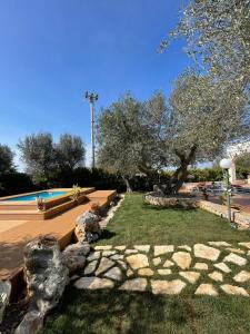 a garden with a swimming pool and trees and rocks at Villa Dama in Cisternino