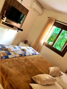 1 dormitorio con cama y ventana en Pousada Cantinho, en Gramado