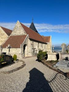 an old stone church with a cross in front of it at Magnifique Appartement l'Aigrette in Dieppe