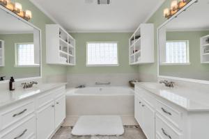 a white bathroom with two sinks and a tub at Beauty on the Water! Lake House near the beaches! in Galveston