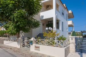 une maison blanche avec une clôture devant elle dans l'établissement Armonia Apartments, à Almyrida