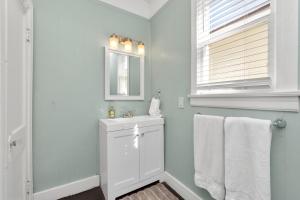a white bathroom with a sink and a mirror at Cozy Historic Galveston House-8 min walk to beach! in Galveston +38 photos