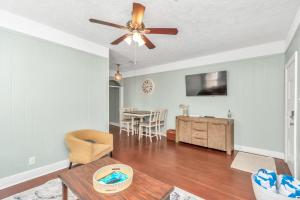 a living room with a ceiling fan and a table at Cozy Historic Galveston House-8 min walk to beach! in Galveston