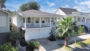 a white house with a porch and a garage at Cozy Historic Galveston House-8 min walk to beach! in Galveston