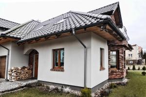 Biały dom z czarnym dachem w obiekcie Willa Vita - Apartment z kominkiem i dużym tarasem, Sauna, Jacuzzi, Altana z Grill, z możliwością wynajmu dotakowych pokoi - Schönes Appartement mit Kamin und großer Terrasse, Sauna, Jacuzzi, Pavilion mit Grill und der Option zusätzliche Zimmer zu mieten w Stegnie