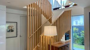 uma escada de madeira numa sala de estar com um candeeiro em Stylish Townhouse em Auckland