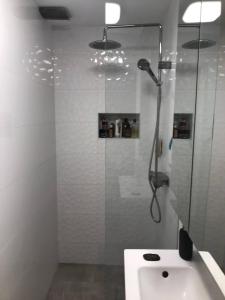 La salle de bains blanche est pourvue d'une douche et d'un lavabo. dans l'établissement Aida, à Ljubljana