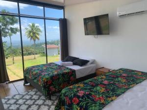 two beds in a room with a large window at Villa Aura in Fortuna