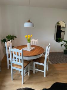 een eettafel en stoelen met een vaas met bloemen bij Gemütliche Wohnung am Federsee in Bad Buchau