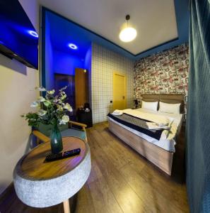 a bedroom with a bed and a table with a vase of flowers at La Casa Hotel Yerevan in Yerevan