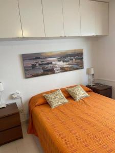 um quarto com uma grande cama laranja e 2 almofadas em Apartamento con Piscina en Llança em Llançà
