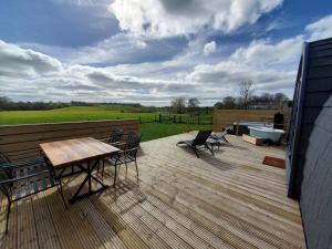eine Terrasse mit einem Tisch, Stühlen und einer Badewanne in der Unterkunft Riding Gate Lodge in Charlton Musgrove