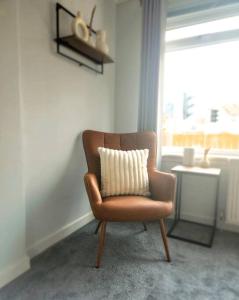 a chair with a pillow in a room with a window at Quirky, Family Home in Glasgow in Cardonald