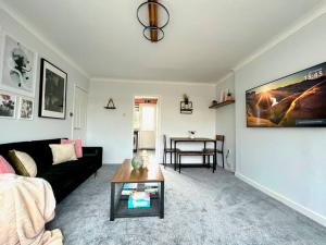un soggiorno con divano nero e tavolo di Quirky, Family Home in Glasgow a Cardonald