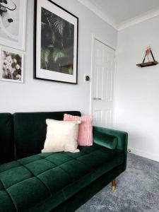 a green couch with two pillows on it in a room at Quirky, Family Home in Glasgow in Cardonald