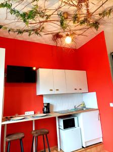 una cucina con pareti rosse, armadi e sgabelli bianchi di Le studio Naturel a Hénin-Beaumont
