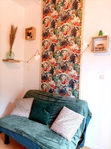Le studio Naturel في هينان بومونت: غرفة مع أريكة خضراء مع ورق جدران فلوري