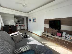 uma sala de estar com um sofá e uma televisão de ecrã plano em Apartamento 2 quartos completo 200 m da praia em Capão da Canoa